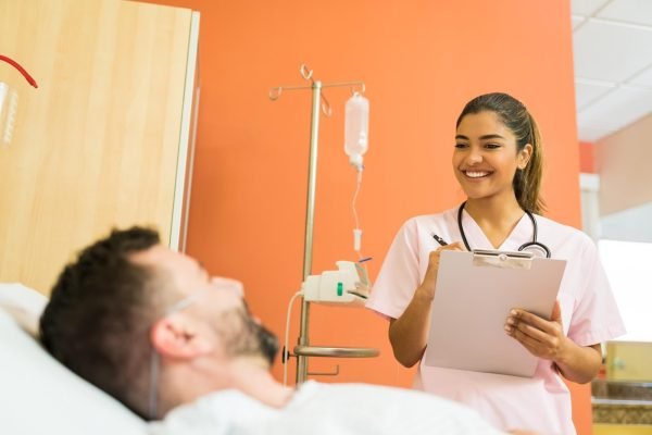 smiling-female-doctor-talking-male-patient-while-reading-reports-hospital